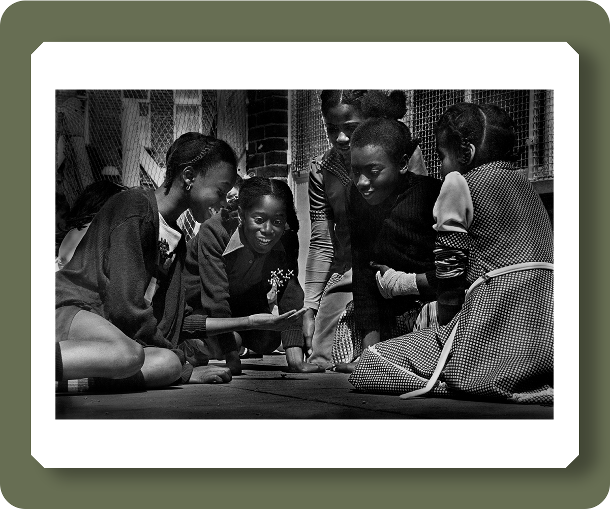 pd3011231 : Girls play a game of jax (jacks) in the school yard during a break. Harlesden, London, February 1979  - Credit: Robert Golden / TopFoto